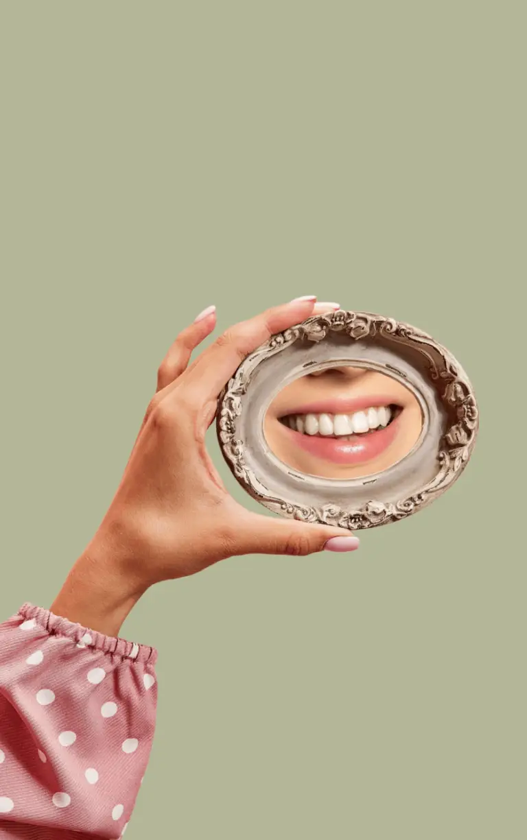 Woman lookint her teeth in mirror after treatment